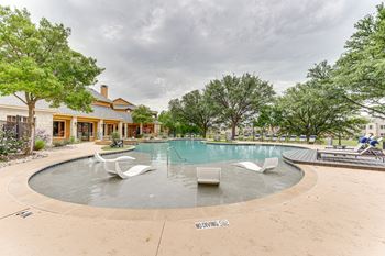 A round pool with white chairs around it at Limestone Ranch Apartments, Texas, 75067